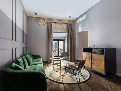 Modern industrial living room with green velvet sofa, round coffee table, and metallic chairs.