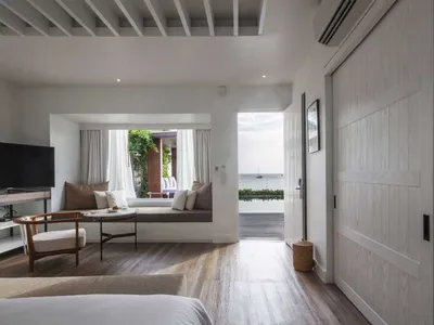 Modern hotel suite featuring white wood, a seating area, and a view of the ocean.