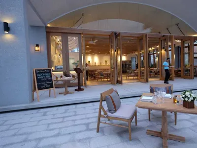 Modern restaurant interior with wooden furniture and open doors to dining area