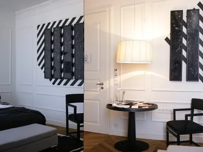 A modern bedroom featuring black and white decor, with a bed, bench, and lamp.