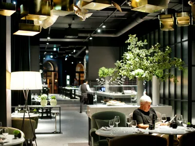 A modern cafe with metallic lighting, glass elements, and green plants.