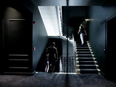 A modern hotel staircase with metal railings and black walls.