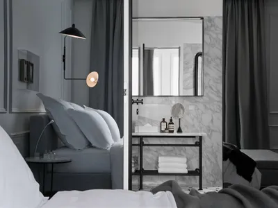Modern minimalist bedroom with dark gray curtains, marble bathroom, and metal accents.
