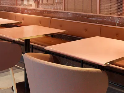 A modern restaurant interior with a unique design featuring a mesh partition made of metal rods and a marble counter top.