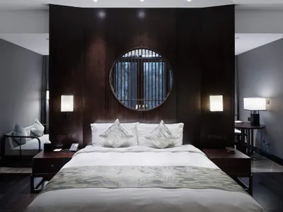 A minimalist bedroom with a bed, nightstands, and a round window.