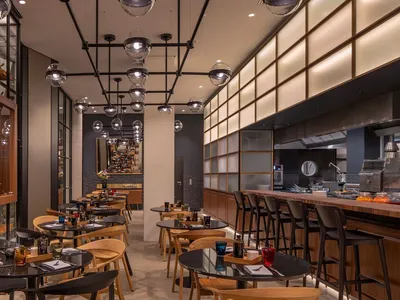 現代工業風餐廳室內，搭配俐落黑色吊燈、木質餐桌與玻璃欄杆。