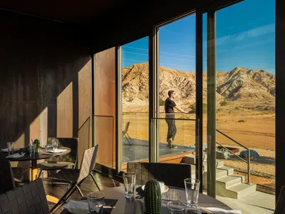 A modern restaurant interior with concrete, glass, and stainless steel elements.