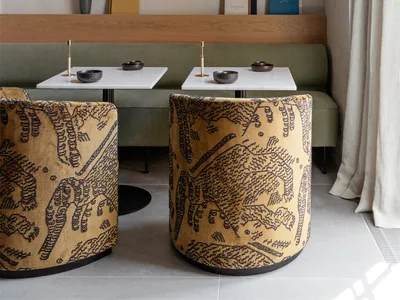 A cafe interior featuring patterned sofas, a concrete countertop, and a wooden bench seating area.