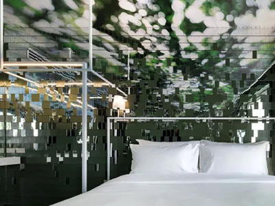 A minimalist bedroom with a large mirror on the wall, creating an illusion of a larger space.