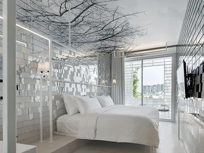 A modern minimalist bedroom featuring mirrored metallic tiles on the walls and ceiling, creating a reflective and spacious en