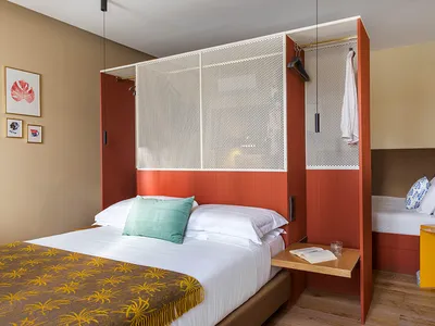 Modern minimalist bedroom featuring a metal-framed wooden bed, a foldable desk, and a small side table.