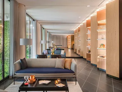 Modern lobby featuring sleek glass walls, wooden accents, and concrete flooring.
