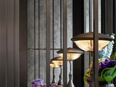 A modern hotel lobby featuring marble surfaces and metal accents with a bouquet of purple flowers on display.