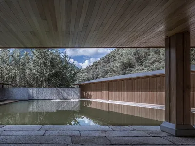 Swimming pool area with wooden and stone finishes in a minimalist hotel resort design.