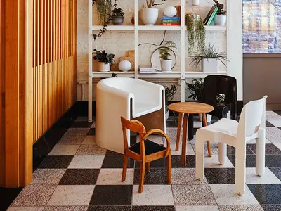 Modern restaurant cafe interior with hanging plants, white shelves, and wooden furniture.