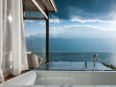 A luxurious hotel room featuring a modern bathroom with a white bathtub overlooking the ocean.