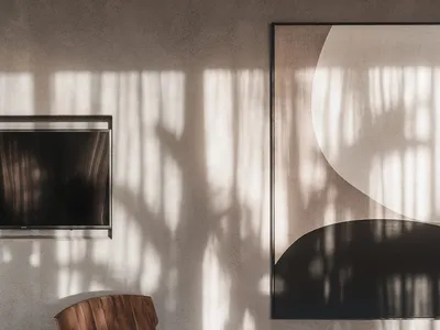 Minimalist bedroom with wooden furniture, large abstract artwork, and natural light streaming in
