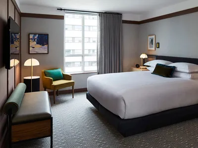 A well-designed, minimalist hotel room featuring modern furniture and textured fabrics.
