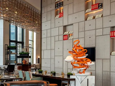 A modern restaurant with metal and leather seating, marble countertops, and a glass art installation.