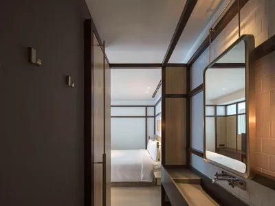 Minimalist bedroom with white bedding, wooden headboard, and concrete floors and walls.