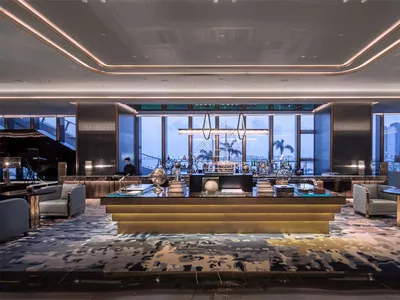 A modern hotel bar with glass, marble, and brass accents.