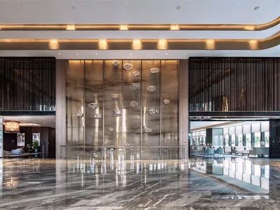 Modern interior design of a hotel lobby featuring glass walls and marble floor.