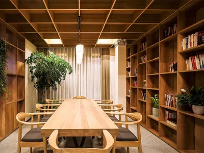 現代圖書館或書房，搭配木質家具與書架，設有木桌、椅子及盆栽植物。