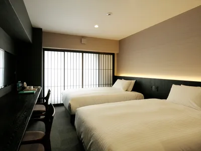 Modern minimalist hotel room with a textured fabric bedspread and a television mounted on the wall.