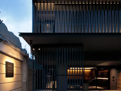 Modern exterior of a hotel building with metallic cladding on a concrete facade at dusk.