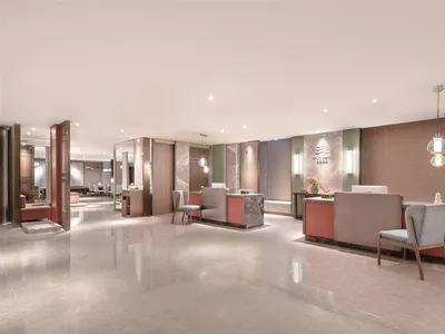 A spacious, modern hotel lobby features elegant marble finishes and contemporary glass elements.