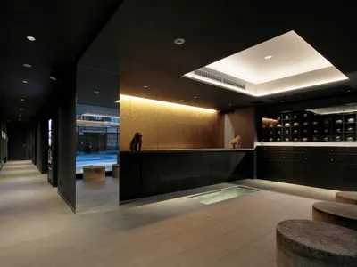 Modern hotel reception area with black interior design and lighting features.