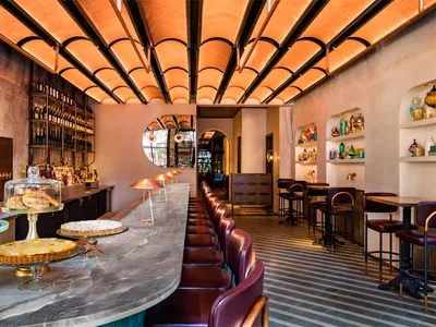 Modern restaurant interior with a concrete bar counter and high-top seating.