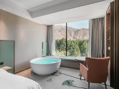 Modern, minimalist bedroom featuring concrete flooring, glass window, and furniture.