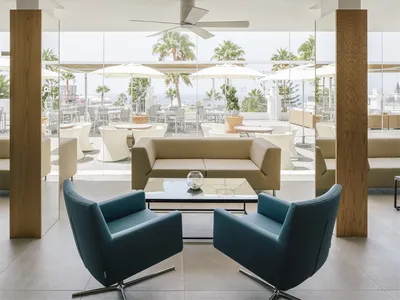 A modern hotel lounge area with white furniture and a glass table.