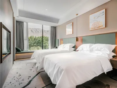 Modern minimalist hotel room with white textiles and green accent colors.
