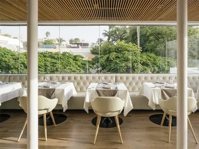 Table setting in a modern restaurant with white leather banquettes and white tablecloths.