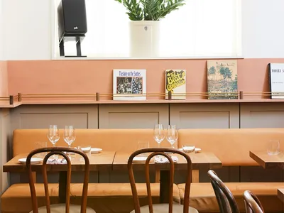 Interior design of a cafe featuring mid-century modern furniture with wooden tables and chairs, brown leather seating, and de