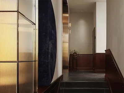 A hotel corridor featuring illuminated metal panels and dark stone stairs.