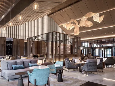 A stylish modern hotel lobby with contemporary furniture, wooden walls, and metal accents.