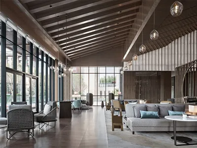A spacious, modern industrial hotel lobby featuring glass walls, concrete flooring, and wooden accents.