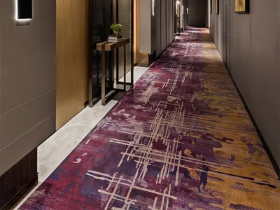 An elegant hotel hallway with modern design elements and a wood-textured floor, featuring a carpet with geometric patterns an