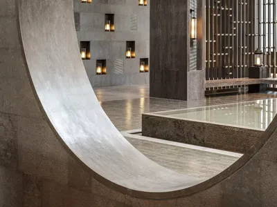Modern hotel lobby featuring concrete walls and floors with warm lighting.