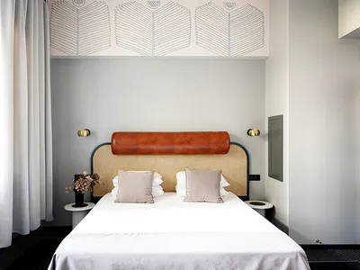 A minimalist bedroom featuring a bed with a leather headboard and white bedding.