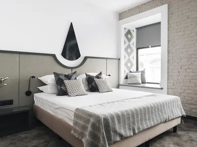 Modern minimalist bedroom with concrete walls, fabric bedding, and wooden accents.