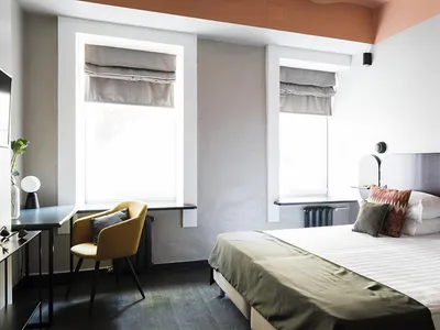 A minimalist bedroom with a white bed, green blanket, and simple decor.