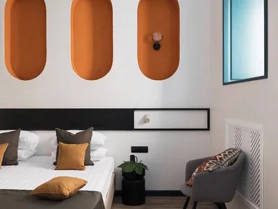 Modern bedroom with concrete walls, wooden floor, and fabric bedding and furniture.