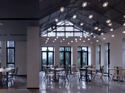 Modern industrial restaurant interior featuring metallic finishes, glass elements, and concrete surfaces.