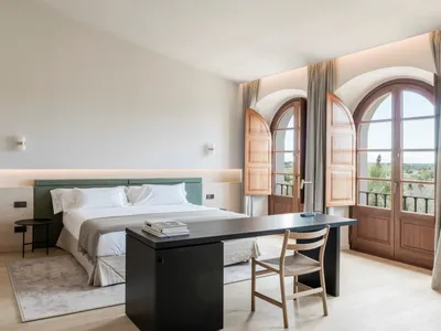 Modern, minimalist bedroom featuring a wooden bed, fabric bedding, and glass windows.