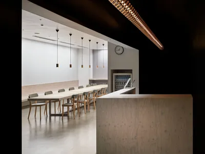 簡約餐廳室內，長形木桌搭配吊燈，以及接待櫃檯。