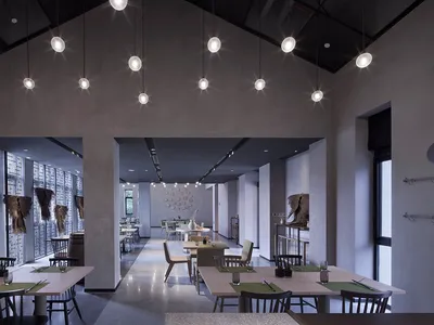 A modern restaurant interior with concrete walls and hanging lights.